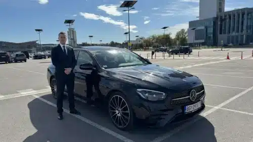 Professional chauffeur standing by his vehicle at Belgrade Airport