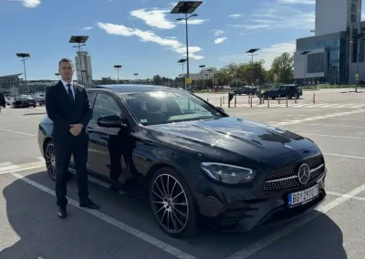 Profesionalni vozač ispred svog vozila parkiranog na beogradskom aerodromu